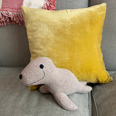 Wool Seal Soft Toy sitting on a sofa